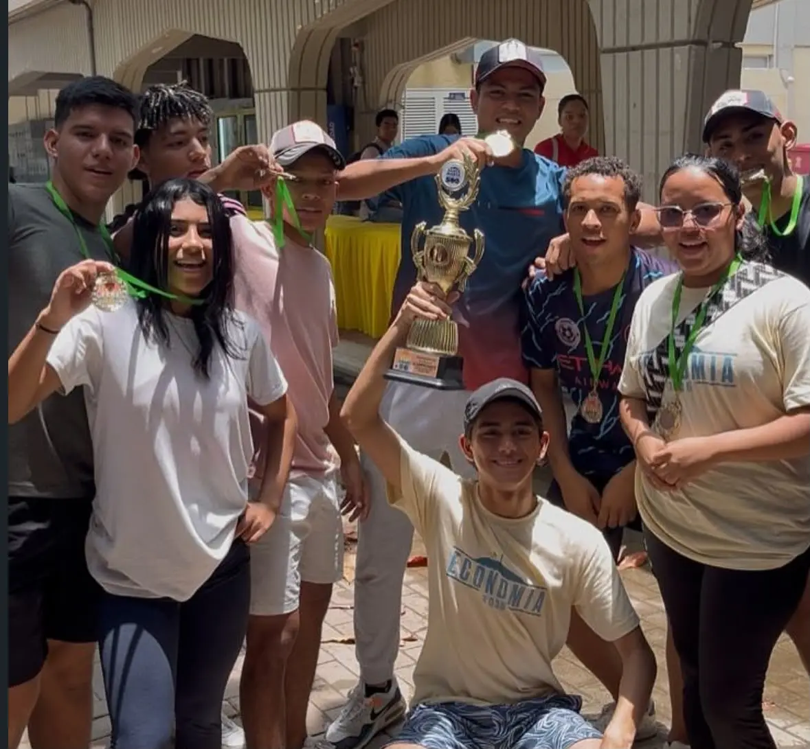 Un equipo posa con un trofeo y medallas en las AsociaOlimpiadas.